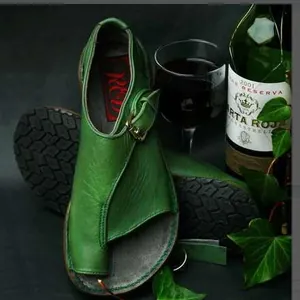 Detailed macro view of green vintage leather toe-loop flat sandals with bronze buckle closure