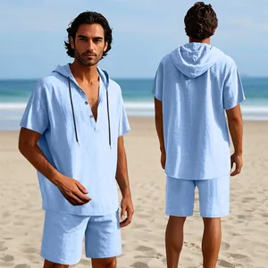 Completo uomo azzurro in lino con camicia con cappuccio e pantaloncini sulla spiaggia.