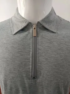 Close-up detail of a grey knit polo shirt featuring a sleek half-zipper and polo collar.