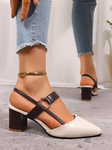 Detailed close-up of stylish pointed-toe block-heel slingback shoes in cream and brown.