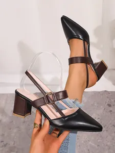 Elegant detail view of black pointed-toe chunky heel pumps with brown Mary Jane ankle straps.