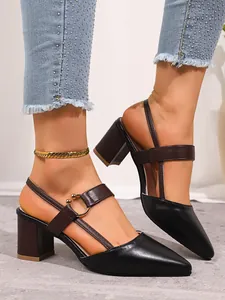 Close-up detail of black and brown pointed-toe block heel Mary Jane sandals on feet