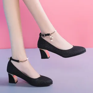 Close-up of black glitter high heels with chunky heel and jeweled ankle strap.