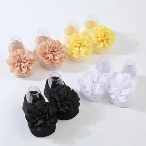 Primer plano de calcetines para bebé con grandes flores de gasa multicapa en cuatro colores.