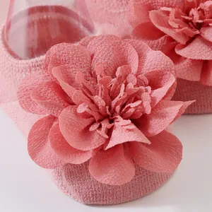 Detalle en primer plano de calcetines rosas para bebé con una gran flor de gasa en 3D.