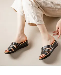 Gros plan sur des sandales compensées en cuir noir élégantes portées avec un pantalon