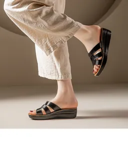 Vue latérale de sandales compensées confortables en cuir noir pour femmes en décor élégant