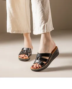 Vue détaillée de sandales compensées en cuir noir portées avec un pantalon en lin d'été.