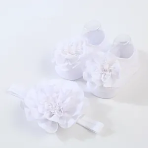 Detalle del conjunto de calcetines y diadema blanca para bebé con flores de gasa suave.