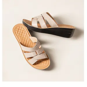 Gros plan de sandales compensées en cuir beige avec brides tressées et semelle noire
