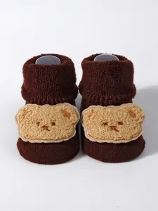 Close-up detail of thick brown baby floor socks featuring a plush cartoon bear patch
