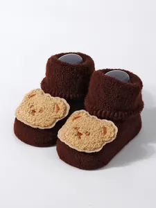 Close-up of thick brown baby knit socks featuring a cute embroidered bear detail.
