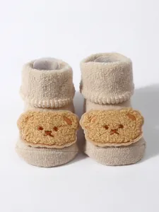 Detail of thick terry baby floor socks featuring a cute plush cartoon bear patch decoration