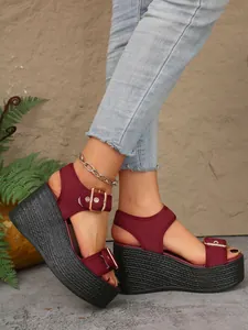 Detailed side view of burgundy mesh wedge sandals featuring woven platform and buckles