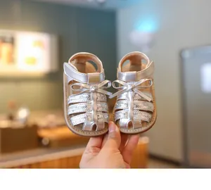 Detailopname van zilveren baby prinsessensandalen met pailletten en een strik.