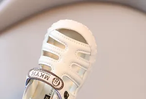 Gros plan de sandales en cuir blanc pour tout-petits avec un design à bout fermé évidé