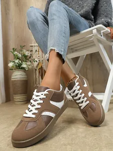 Gros plan de baskets GAT rétro marron pour femmes avec lacets blancs sur un mannequin