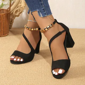 Vue rapprochée de sandales à talons hauts noirs avec boucle dorée à la cheville.