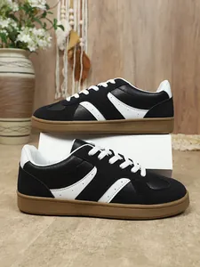 Vue latérale de baskets GAT rétro classiques noires et blanches pour femmes en studio.