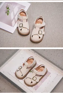 Detail of cream closed-toe girl sandals with adjustable buckle strap