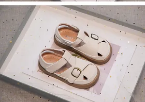 Detail view of beige closed-toe children's sandals with metallic buckle and soft sole design