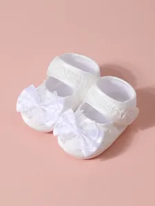 Vue détaillée de chaussures de princesse pour bébé en dentelle blanche avec de beaux nœuds