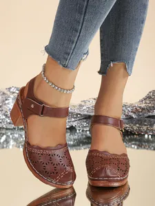 Close-up showing the intricate hollow-out patterns on retro brown leather chunky heel sandals