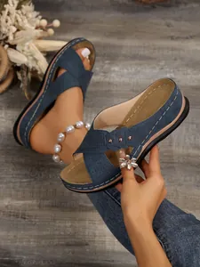 Gros plan détaillé de mules à talons compensés bleu marine avec jolis détails floraux ajourés