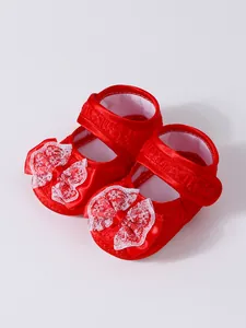 Vue détaillée de chaussures princesse rouges pour bébé avec nœud en dentelle