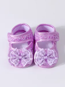 Détail de chaussures de princesse pour bébé violettes avec dentelle et nœuds délicats