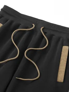 Close-up of ribbed waistband and khaki drawstring on black men's joggers
