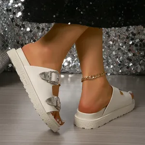 Détail de sandales à plateforme blanches avec boucles argentées et semelle texturée