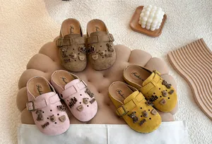 Detailopname van kinderklompen van suède-achtig materiaal in roze, geel en bruin.