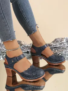 Close-up side view of vintage navy blue hollow-out sandals with chunky wooden heels