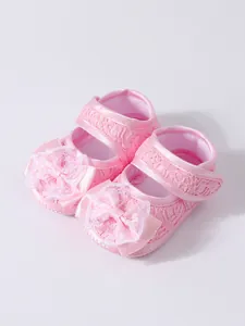 Vue détaillée des chaussures de princesse bébé en dentelle rose avec nœud ruban