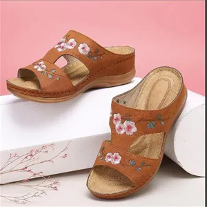 Vue détaillée de sandales compensées brunes avec broderie florale et design ajouré élégant.