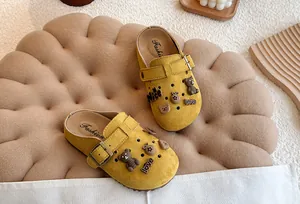 Detailweergave van gele kinderklompen met schattige berenbedeltjes en verstelbare gesp.