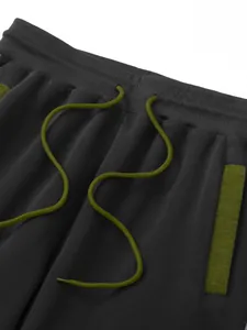Close-up detail of men's dark grey sweatpants featuring olive green drawstring