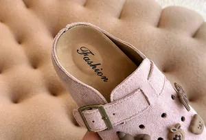 Detail van roze suède kinderklompen met Fashion-logo en een verstelbare metalen gesp.