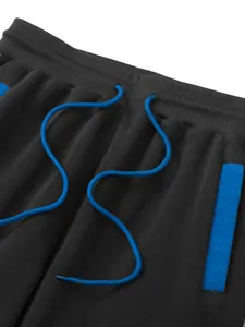 Macro detail of men's black athletic joggers featuring blue drawstring and pocket