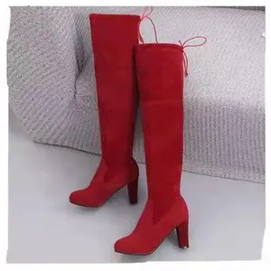 Detail view of red suede over-the-knee boots with chunky high heels and back lace-up.