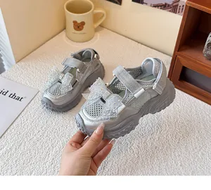 Detailansicht der silbernen Mädchen-Sandalen mit glitzernder Schleife und Netzmaterial