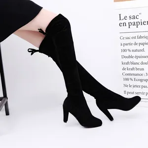Stylish side view of black suede over-the-knee boots with high heels and tie detail