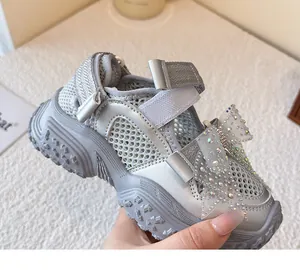 Nahaufnahme einer silbernen Mädchen-Sandalette aus Mesh mit einer großen Glitzerschleife