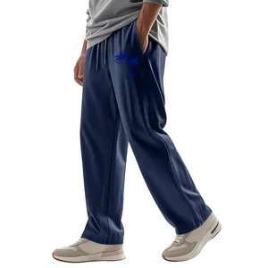 Detail of men's loose linen trousers featuring a blue palm tree print in navy blue.
