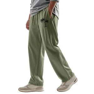 Close-up of men's loose linen trousers with palm tree print in sage green