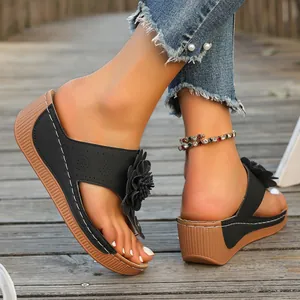 Detail view of black women's wedge sandals with flower decoration and brown sole