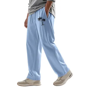 Close-up detail of light blue men's linen pants featuring a black palm tree print.