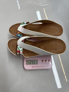 Weight measurement of embroidered wedge flip-flop sandals showing 233.1 grams on scale.