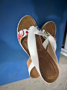 Detail shot showing the top-down view of white thong wedge sandals with colorful floral embroidery